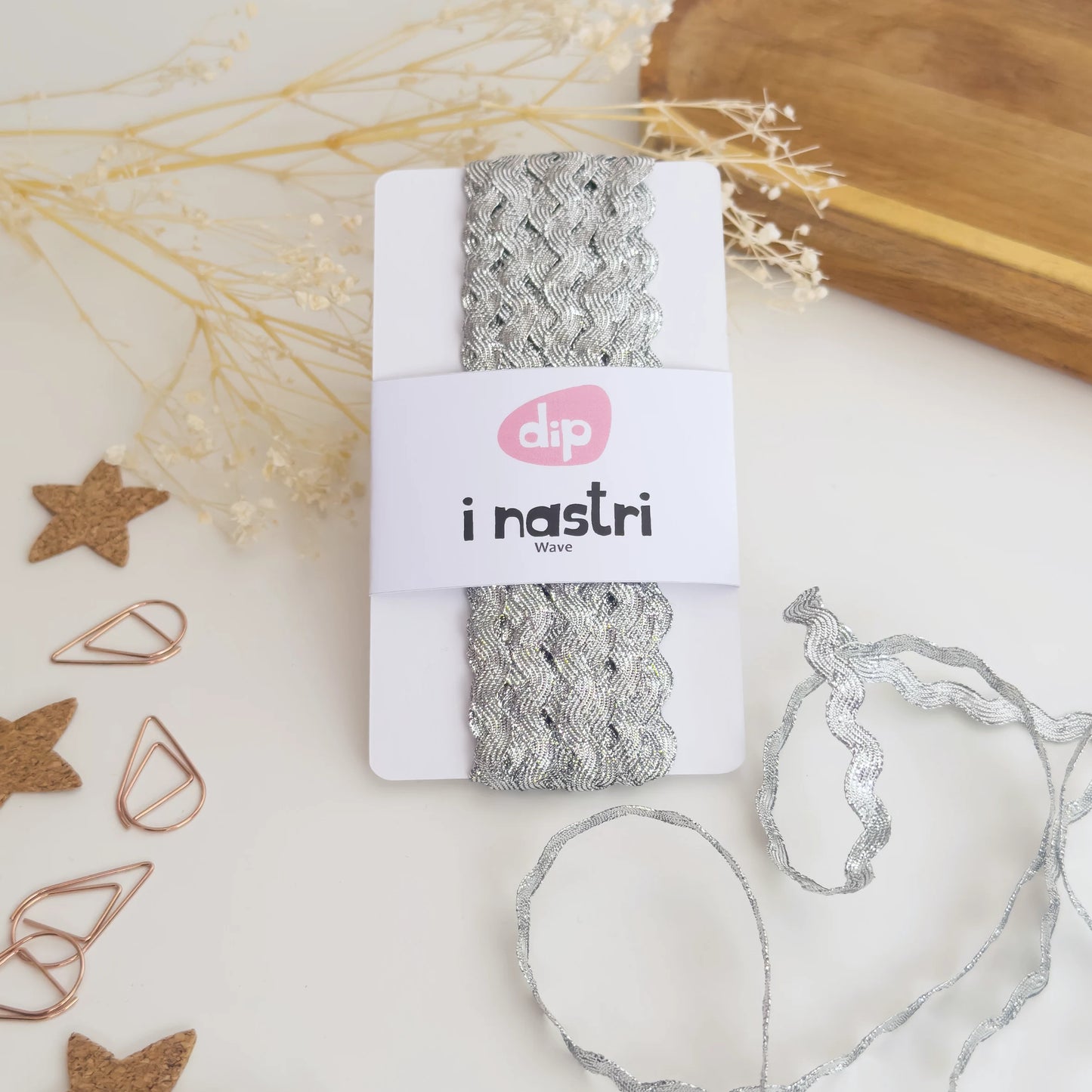 Bobina di nastro ondulato argento metallizzato per decorazioni e pacchetti regalo artigianali.