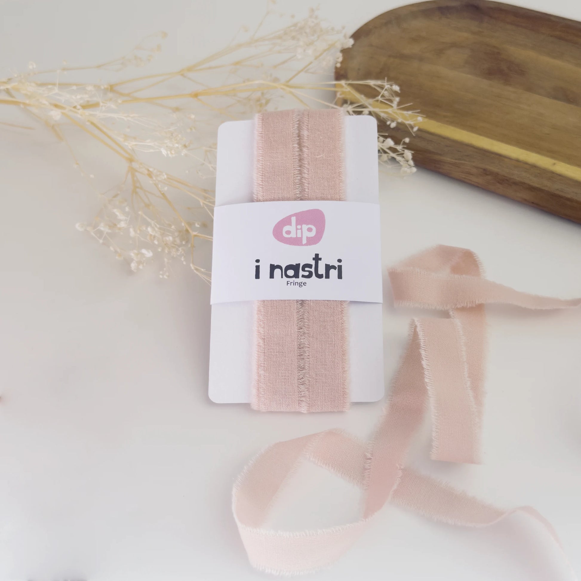 Bobina di nastro in cotone sfrangiato rosa antico per decorazioni sartoriali e confezioni di lusso.