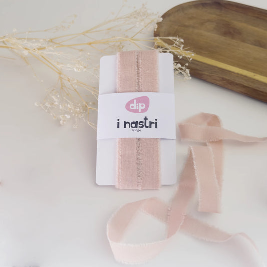 Bobina di nastro in cotone sfrangiato rosa antico per decorazioni sartoriali e confezioni di lusso.